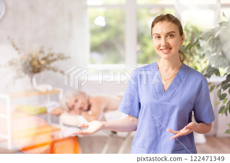 Female physiotherapist poses against background of spa salons office. Female physiotherapist poses against background of spa salons office. 122471349