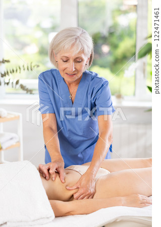 Mature female masseur performs stroking and rubbing during spa in abdominal area for woman client. Mature female masseur performs stroking and rubbing during spa in abdominal area for woman client. 122471461