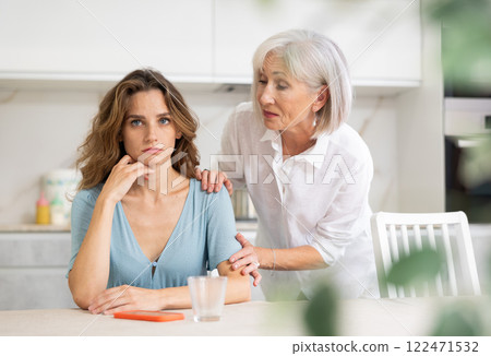 Elderly mother asks for forgiveness from her adult daughter and calms her down after a domestic quarrel in kitchen 122471532