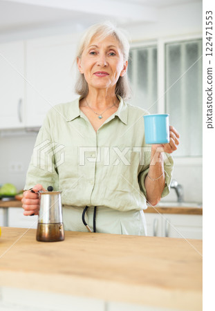 Relaxed elderly woman drinking coffee at kitchen 122471553