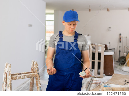 Discontented teenager with bunch of money he earned on first job in building site 122471560