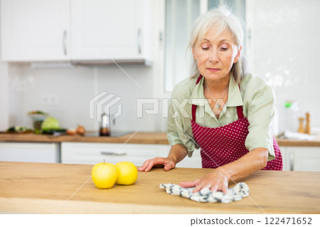 Mature woman cleaning kitchen table at home Mature woman cleaning kitchen table at home 122471652