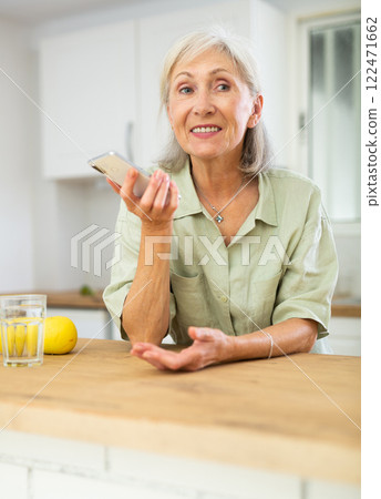 Positive senior woman using phone at home Positive senior woman using phone at home 122471662