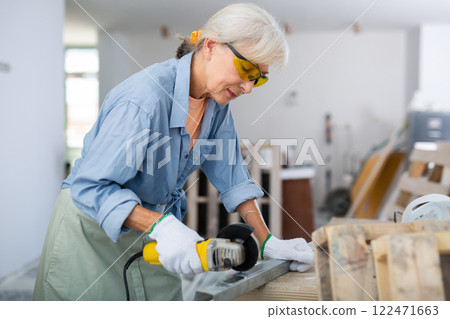 Mature woman renovating home, cutting metal profile Mature woman renovating home, cutting metal profile 122471663
