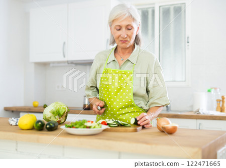 Cheerful elderly woman cooking salad at home Cheerful elderly woman cooking salad at home 122471665