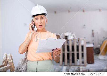 Woman talking on phone at renovating house Woman talking on phone at renovating house 122471710