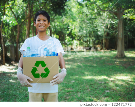 Boy hold cardboard boxes for recycling and holding a recycle bin with plastic bottles in the outdoors, Reduction environmental pollution and recycle concept, Plastic-free, Junk food plastic packaging. Boy hold cardboard boxes for recycling and holding a recycle bin with plastic bottles in the outdoors, Reduction environmental pollution and recycle concept, Plastic-free, Junk food plastic packaging. 122471772