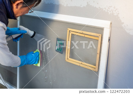 Man washing screen door DIY spring cleaning 122472203