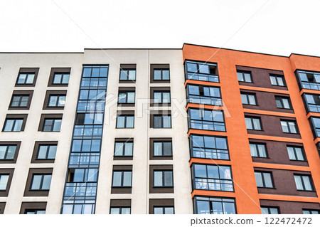Modern apartment building facade, featuring beige, orange, and brown tones, with dark-framed windows, low angle view. Urban housing concept Modern apartment building facade, featuring beige, orange, and brown tones, with dark-framed windows, low angle view. Urban housing concept 122472472