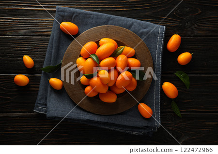 Kumquat on plate and towel on wooden background, top view 122472966