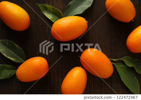 Kumquat and leaves on dark wooden background, top view Kumquat and leaves on dark wooden background, top view 122472967