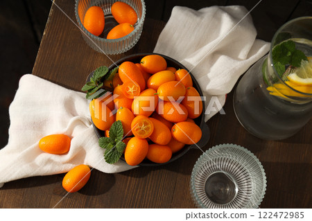 Kumquat in bowl, towel and glass on wooden background, top view Kumquat in bowl, towel and glass on wooden background, top view 122472985