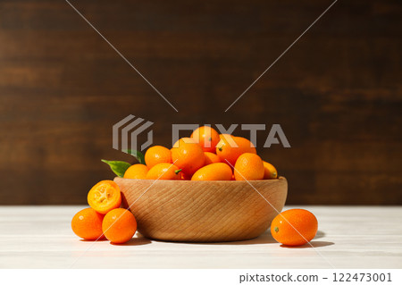 Kumquat in wooden bowl on wooden background 122473001