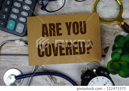 Are You Covered? text with calculator, magnifying glass and alarm clock on wooden background Are You Covered? text with calculator, magnifying glass and alarm clock on wooden background 122473375