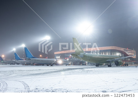Passenger airplanes on the airport apron next to the terminal in a snowy winter night 122473453