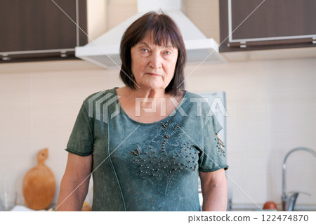 Woman in a green shirt stands in front of a kitchen sink 122474870