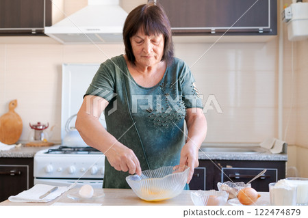 Woman is making a cake in a kitchen Woman is making a cake in a kitchen 122474879