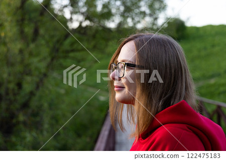 Contemplative moment by the wooden bridge surrounded by lush greenery in the golden hour light Contemplative moment by the wooden bridge surrounded by lush greenery in the golden hour light 122475183