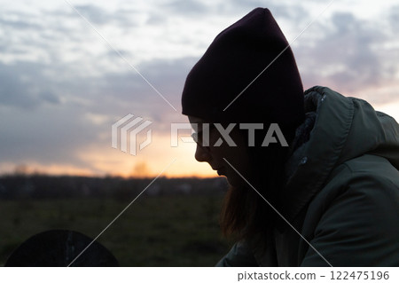 Contemplative silhouette against a serene dusk landscape with a colorful sky Contemplative silhouette against a serene dusk landscape with a colorful sky 122475196