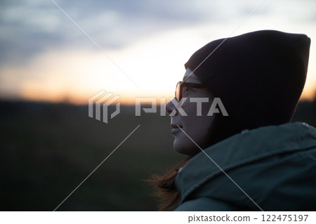 Contemplative moment at twilight with a serene woman gazing at the horizon 122475197