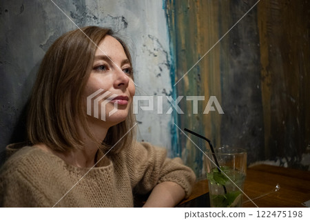 Woman in a cozy cafe reflecting on life while enjoying a refreshing drink in a vibrant atmosphere Woman in a cozy cafe reflecting on life while enjoying a refreshing drink in a vibrant atmosphere 122475198