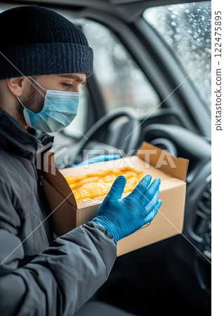 Delivery Driver Wearing Gloves and Mask Holding Food Box Inside Vehicle During Rainy Day 122475895