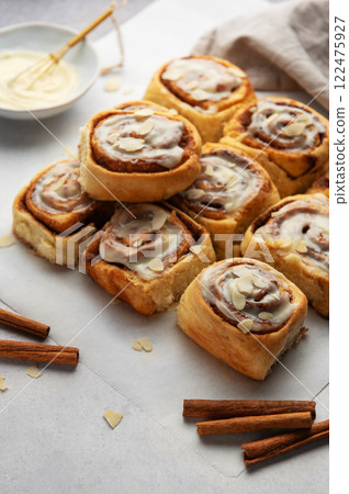 Freshly baked cinnamon rolls topped with icing and almond slivers 122475927