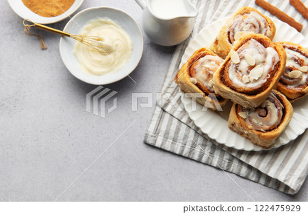 Freshly baked cinnamon rolls topped with icing and almond slivers 122475929