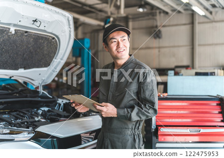Automobile mechanic checking the engine compartment of a car - Acceptance inspection (vehicle inspection and regular inspection) Automobile mechanic checking the engine compartment of a car - Acceptance inspection (vehicle inspection and regular inspection) 122475953