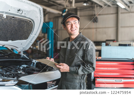 Automobile mechanic checking the engine compartment of a car - Acceptance inspection (vehicle inspection and regular inspection) Automobile mechanic checking the engine compartment of a car - Acceptance inspection (vehicle inspection and regular inspection) 122475954