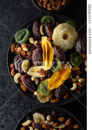 Dried tropical fruits, nuts, and raisins in black plate. Dried tropical fruits, nuts, and raisins in black plate. 122476996