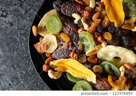 Dried tropical fruits, nuts, and raisins in black plate. Dried tropical fruits, nuts, and raisins in black plate. 122476997
