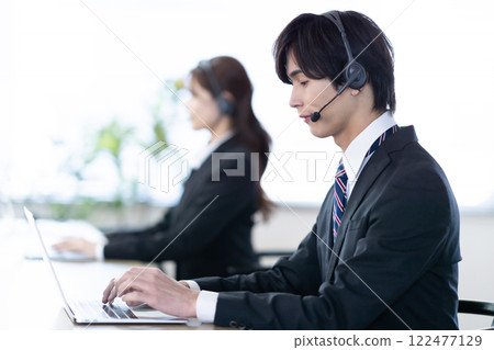 Young man receiving a call at a call center Young man receiving a call at a call center 122477129
