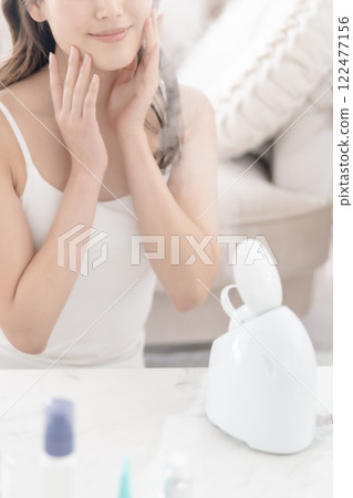 年輕女子在臉頰上敷臉部蒸氣機，沒有臉 122477156