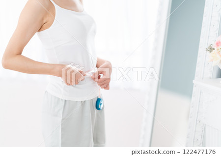 Young woman measuring her waist 122477176