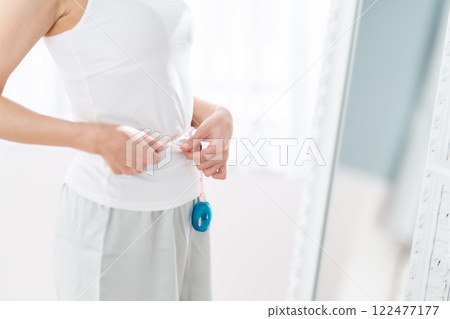 Young woman measuring her waist Young woman measuring her waist 122477177