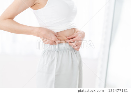 Young woman pinching her waist Young woman pinching her waist 122477181