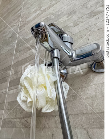 Running tap water on white bath sponge, bathroom closeup. High quality photo Running tap water on white bath sponge, bathroom closeup. High quality photo 122477753