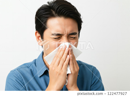 一名男子打噴嚏時用紙巾摀住嘴巴和鼻子 122477927