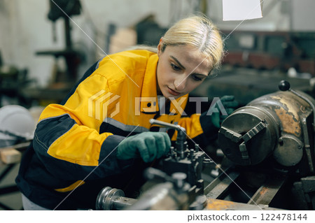 caucasian women worker working in heavy metal industry factory with steel part lathe machine caucasian women worker working in heavy metal industry factory with steel part lathe machine 122478144