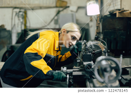caucasian women worker working in heavy metal industry factory with steel part lathe machine 122478145