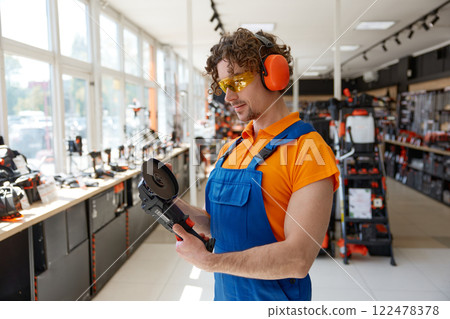 Male seller testing angle grinder at hardware store cropped shot 122478378