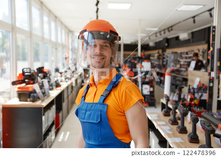 Hardware supermarket worker demonstrating modern protective helmet with visor 122478396