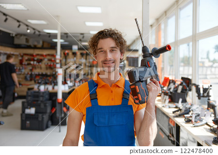 Workman standing with electric power drill manual tool 122478400