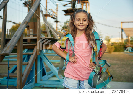 Pretty preteen girl with harness posing for camera over rope park background 122478404