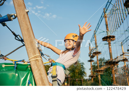 Happy little girl child having fun time at open air rope park 122478429