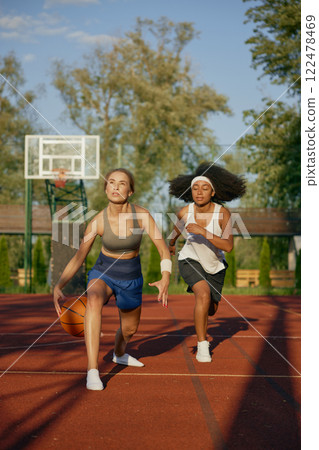 Female basketball players running with ball ready to pass into basket 122478469