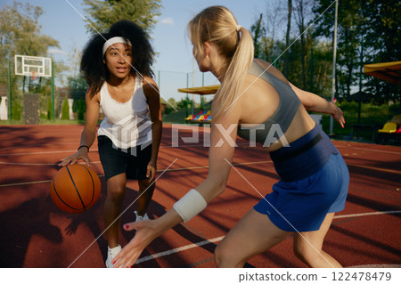 Two girl athlete playing basketball together at outdoor court Two girl athlete playing basketball together at outdoor court 122478479