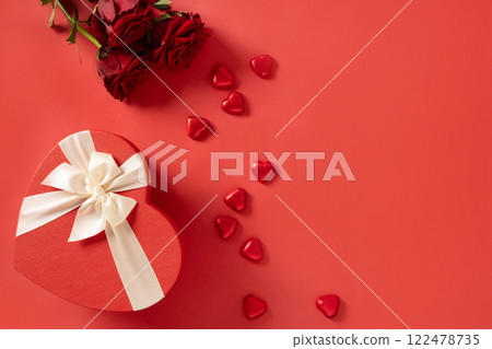 Valentine's day romantic gift, bouquet of red roses and heart shaped chocolate candy sweets on red background. View from above. Greeting card. Copy space. Valentine's day romantic gift, bouquet of red roses and heart shaped chocolate candy sweets on red background. View from above. Greeting card. Copy space. 122478735