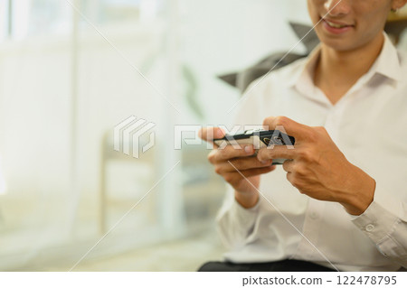 Cropped shot of smiling man enjoying mobile gaming at home Cropped shot of smiling man enjoying mobile gaming at home 122478795